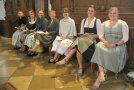 Frauen im Dirndl sitzen in einer Kirche