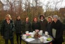 Frauen stehen im Garten mit Tassen in der Hand