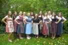 Zwölf Frauen im Dirndl stehen im Garten