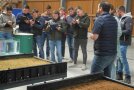 Personen stehen in einer Halle und schreiben auf Klemmbrettern