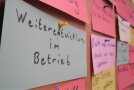 Verschiedene Karten mit Aufschriften hängen an einer Tafel