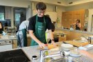 Jugendlicher bereitet Teig zu in einer Schulküche