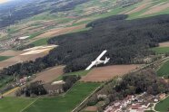 Motorsegler fliegt über Felder und Wiesen