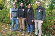 Vier Personen stehen vor einem Baum